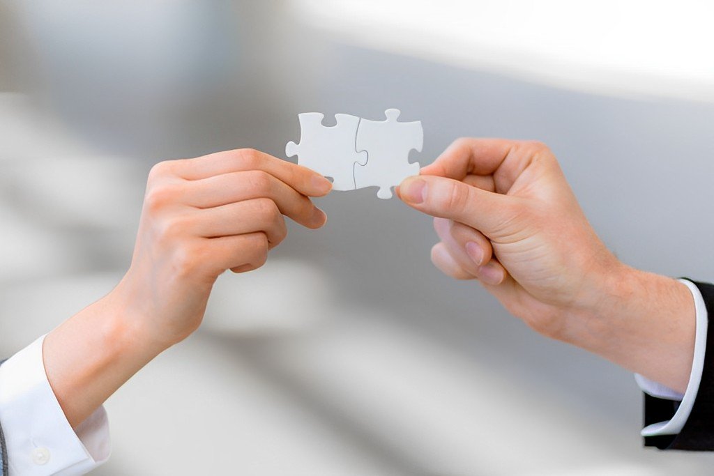 Duas mãos segurando uma peça de quebra cabeça